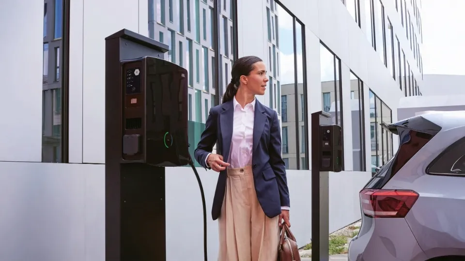Frau an ABL eM4 Twin Wallbox auf Firmenparkplatz – Doppelladestation als VW Wallbox Alternative Frau an ABL eM4 Twin Wallbox auf Firmenparkplatz – Doppelladestation als VW Wallbox Alternative