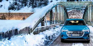Frontansicht des Audi etron in der Farbe blau auf einer Brücke im Winter mit Allrad
