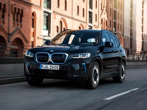 BMW iX3 Elektroauto in der Farbe Blau in der Ansicht von schräg vorne während der Fahrt BMW iX3 Elektroauto in der Farbe Blau in der Ansicht von schräg vorne während der Fahrt