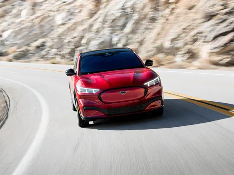 Mustang Mach-E Elektroauto in der Farbe rot Ansicht von der Seite auf einer Bergfahrt Mustang Mach-E Elektroauto in der Farbe rot Ansicht von der Seite auf einer Bergfahrt