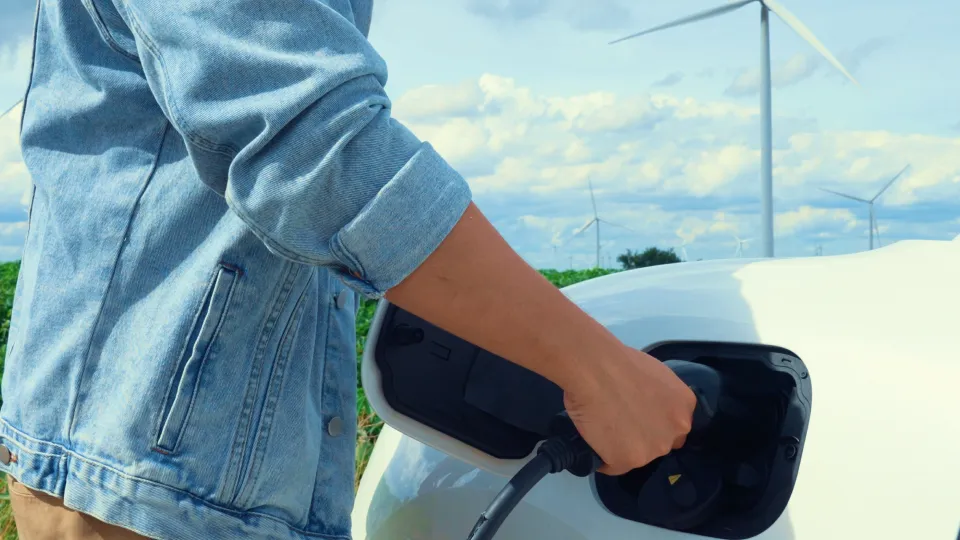 E-Auto wird geladen vor Windrädern E-Auto wird geladen vor Windrädern