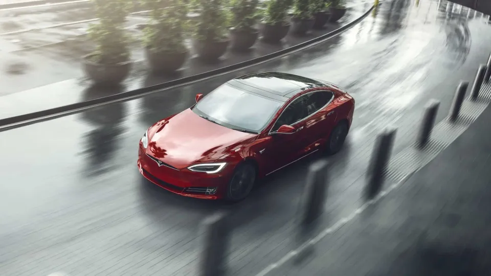 Elektro Limousine Tesla Model S in rot auf Straße bei Regen Elektro Limousine Tesla Model S in rot auf Straße bei Regen