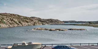 Seitenansicht Polestar 2 mit Anhängerkupplung und Anhänger vor Wasser