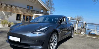 Tesla Model 3 vor Haus am See beim Laden an einer privaten Wallbox