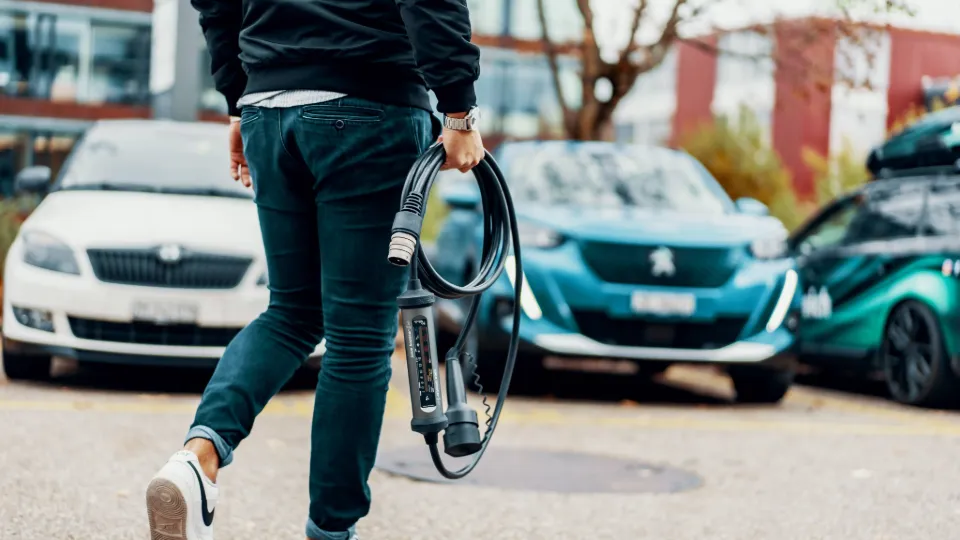 Person trägt Juice Booster 3 air zum E-Auto – beste mobile Wallbox für unterwegs