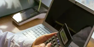 150 kw in PS - Frauenhand mit Taschenrechner vor Laptop