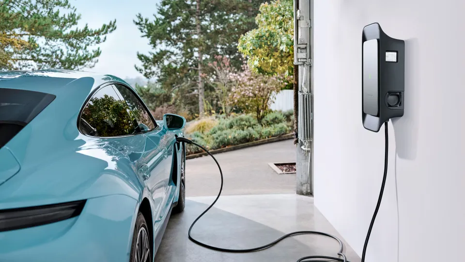 Porsche wird von einer Wallbox des Autoherstellers in der Garage geladen Porsche wird von einer Wallbox des Autoherstellers in der Garage geladen