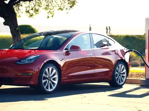 Tesla Model 3 Elektroauto in der Farbe rot Ansicht von Vorne beim Laden an einem Tesla Supercharger Tesla Model 3 Elektroauto in der Farbe rot Ansicht von Vorne beim Laden an einem Tesla Supercharger