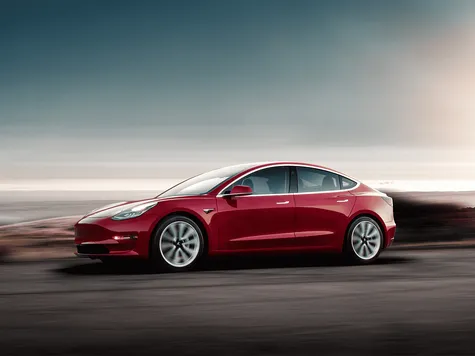 Tesla Model 3 Elektroauto in der Farbe rot Ansicht von schräg Vorne während der Fahrt Tesla Model 3 Elektroauto in der Farbe rot Ansicht von schräg Vorne während der Fahrt