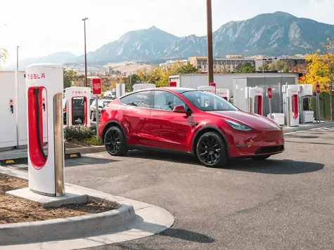 Tesla Model Y in Farbe rot beim Laden am Supercharger Tesla Model Y in Farbe rot beim Laden am Supercharger