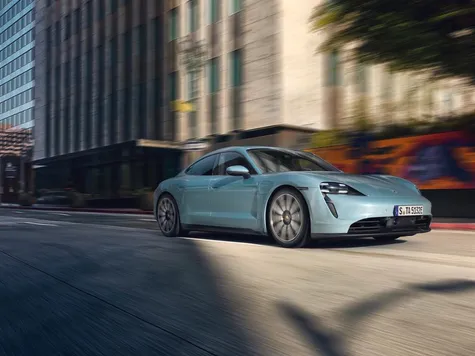 Porsche Taycan Elektroauto in der Farbe blaugrau Ansicht von schräg Vorne während der Fahrt Porsche Taycan Elektroauto in der Farbe blaugrau Ansicht von schräg Vorne während der Fahrt